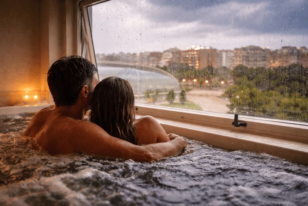 Pareja en jacuzzi privado mirando la lluvia por la ventana de un spa en Valencia